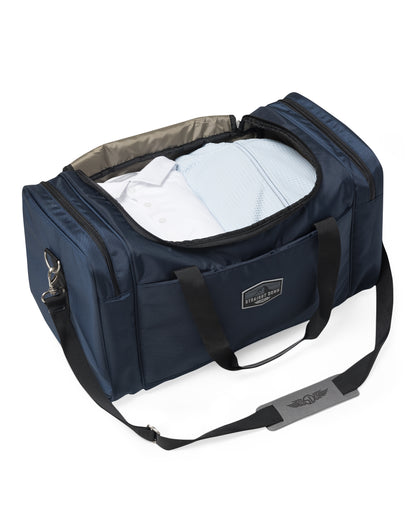 Straight Down Montana Duffle Bag in New Indigo, open top view featuring a navy nylon duffle bag packed with folded clothing, showing the gray interior lining and Straight Down logo strap pad
