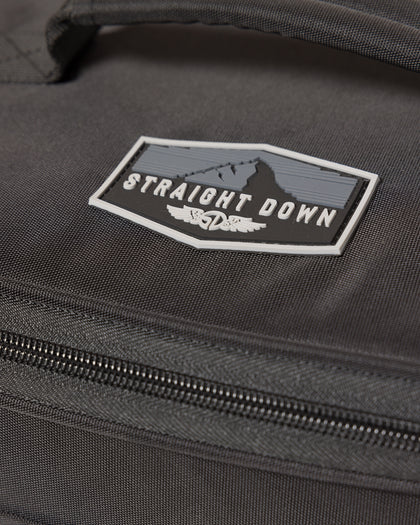 Straight Down Montana Cooler Bag in Black, close-up detail view highlighting the rubber Straight Down mountain badge logo patch on the black ripstop nylon exterior above the zip closure