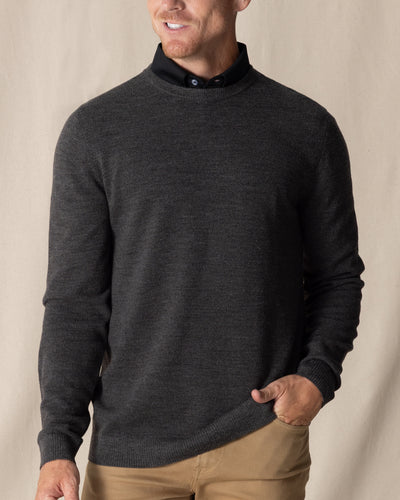 Men's Links Crewneck Sweater in Charcoal Heather, front on-model view featuring a dark heathered gray textured knit fabric with a crew neckline, styled with a black collared shirt and tan pants
