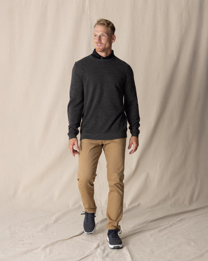 Men's Links Crewneck Sweater in Charcoal Heather, full-length on-model view featuring a dark heathered gray textured knit fabric with a crew neckline, styled with a black collared shirt, tan pants, and dark shoes