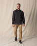 Men's Links Crewneck Sweater in Charcoal Heather, full-length on-model view featuring a dark heathered gray textured knit fabric with a crew neckline, styled with a black collared shirt, tan pants, and dark shoes