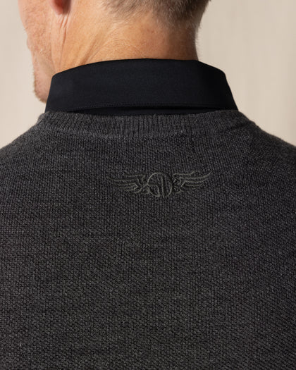 Men's Links Crewneck Sweater in Charcoal Heather, close-up detail view of the tonal embroidered Straight Down winged logo at the upper back against the dark heathered gray textured knit fabric, layered over a black collared shirt