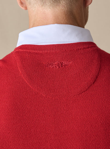 Men's Links Crewneck Sweater in Flag Red, close-up detail view of the tonal embroidered Straight Down winged logo at the upper back against the textured knit fabric, layered over a white collared shirt