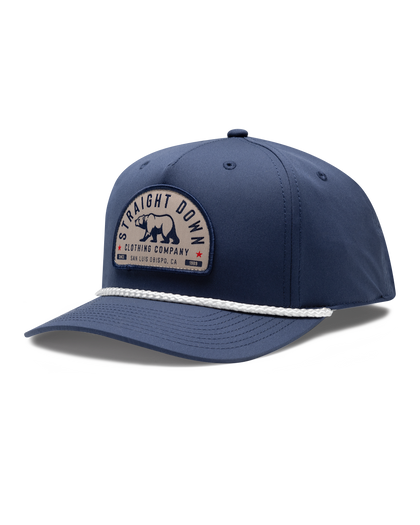 Bear Country Rope Hat in New Indigo, side view featuring a navy structured cap with a woven bear patch reading "Straight Down Clothing Company, San Luis Obispo, CA Since 1989" on the front panel, with a white rope brim detail