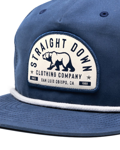 Bear Country Rope Hat in New Indigo, close-up detail view of the cream and navy arched Straight Down Clothing Company bear patch with white rope detail along the brim