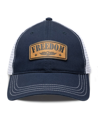 Freedom Hat in Navy, front view featuring a navy structured trucker cap with white mesh back panels, white contrast stitching on the brim, and a tan leather patch reading "Freedom" with the Straight Down logo and star accents centered on the front panel