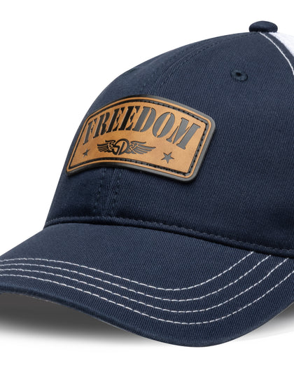 Freedom Hat in Navy, close-up front view featuring a tan leather patch reading "Freedom" with the Straight Down logo and star accents, white contrast stitching detail on the navy structured brim