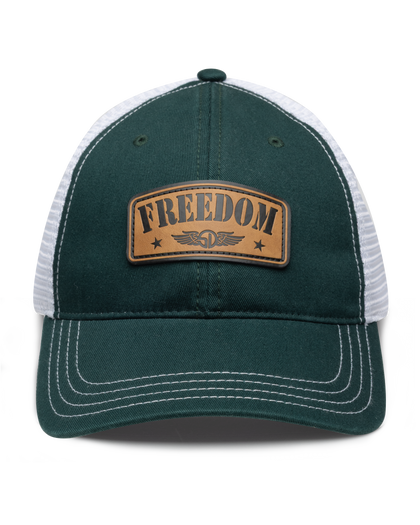 Freedom Hat in Green, front view featuring a green structured trucker cap with white mesh back panels, white contrast stitching on the brim, and a tan leather patch reading "Freedom" with the Straight Down logo and star accents centered on the front panel