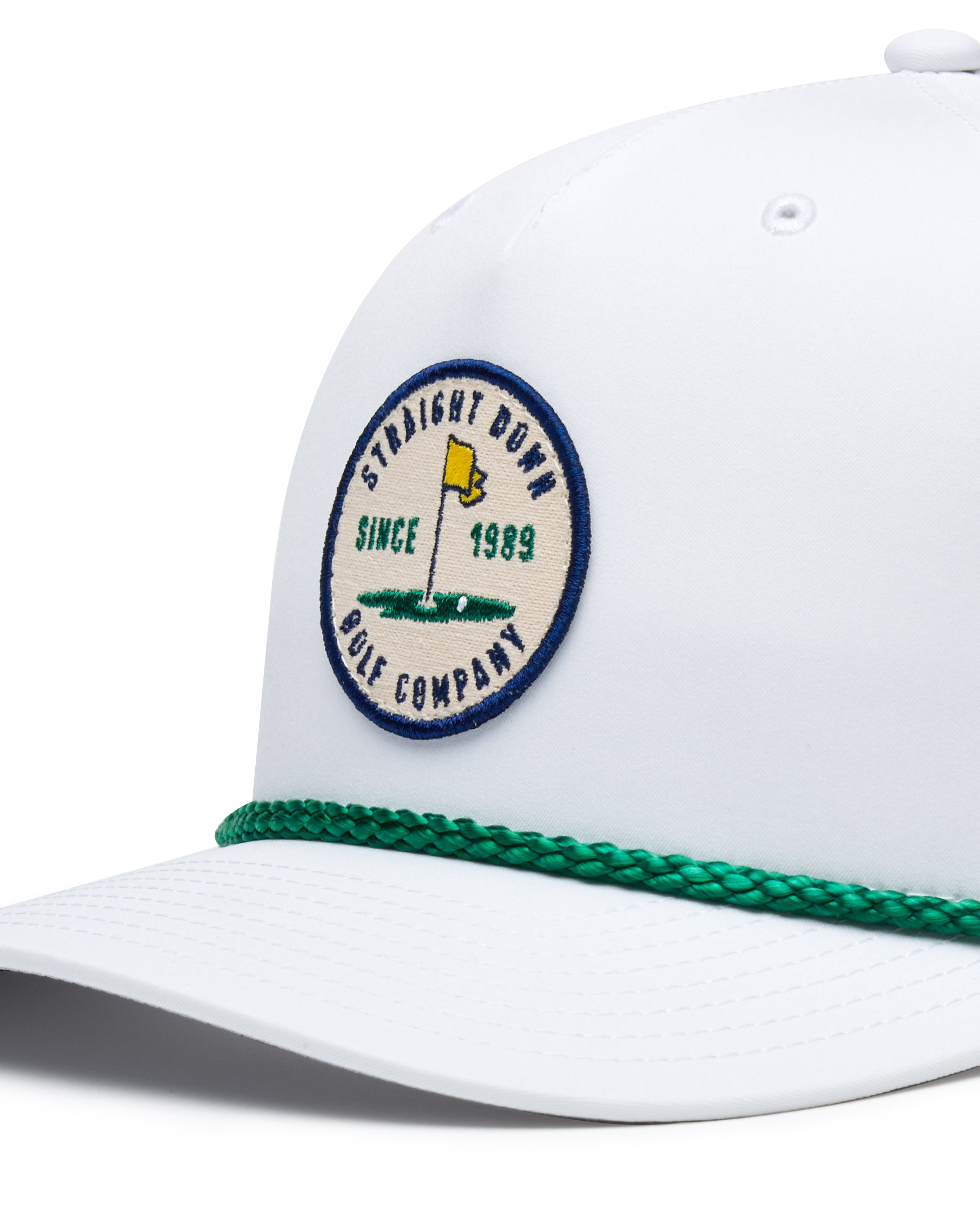 Pin High Rope Hat in White Kelly, close-up detail of the Straight Down Golf Company circular patch depicting a golf hole with a yellow flag and 