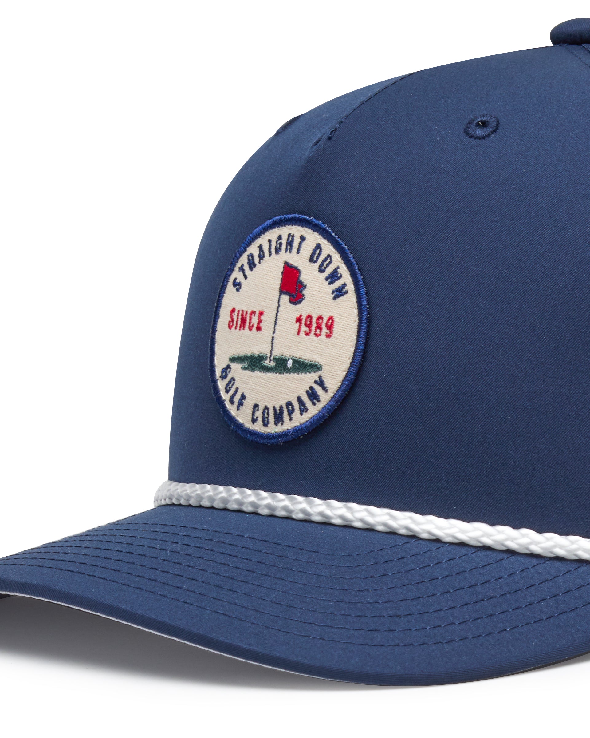 Pin High Rope Hat in Navy, close-up detail of the Straight Down Golf Company circular patch depicting a golf hole with a red flag and 