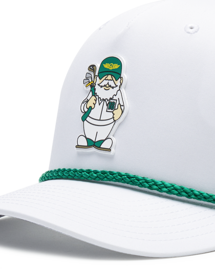 Close up of a white cap featuring a green braided trim along the edge of the brim and a small illustrated golf caddie gnome on the front.