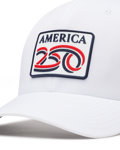 Detail shot of a white structured baseball cap with a curved brim, featuring a front patch that reads 'AMERICA 250' in navy, red, and white. The cap has perforated side panels for ventilation.