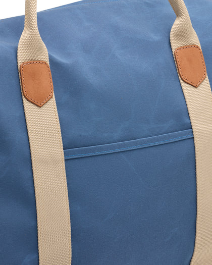 Weekender Bag in Moonlight, close-up detail view of the blue waxed canvas body with tan canvas handles and tan leather trim accents