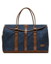 Front view of the Waxed Canvas Duffle Bag in Navy, featuring brown leather handles, leather trim, brass hardware, and a buckle-secured flap closure.