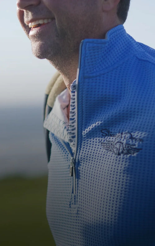 Father’s Day lifestyle banner featuring golfer in Optic Quarter Zip carrying a bag with a coastal backdrop