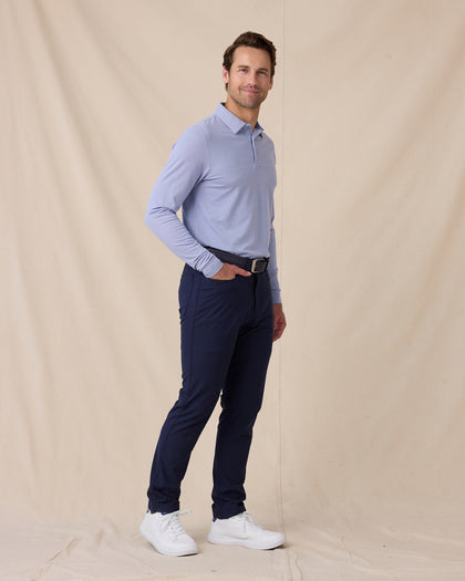 Model wearing the Cambridge Long Sleeve Polo in Chambray Blue paired with navy golf pants