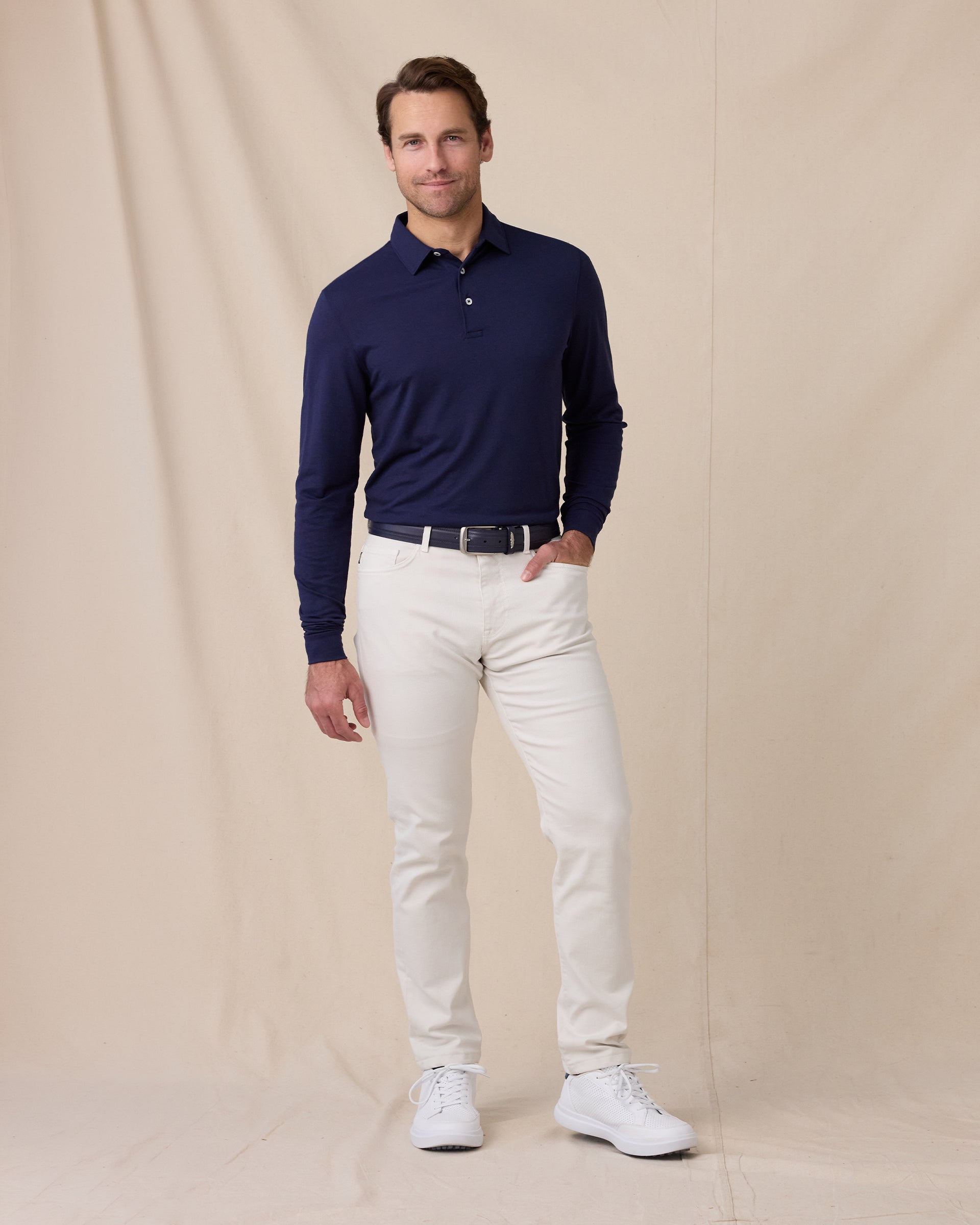 Model wearing the Cambridge Long Sleeve Polo in New Indigo paired with light-colored golf pants