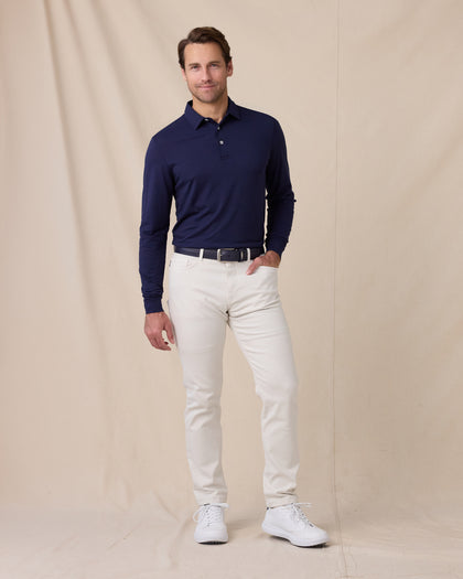 Model wearing the Cambridge Long Sleeve Polo in New Indigo paired with light-colored golf pants