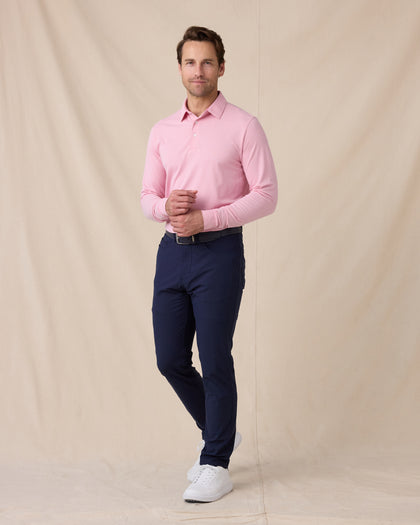 Model wearing the Cambridge Long Sleeve Polo in Punch Pink paired with navy golf pants
