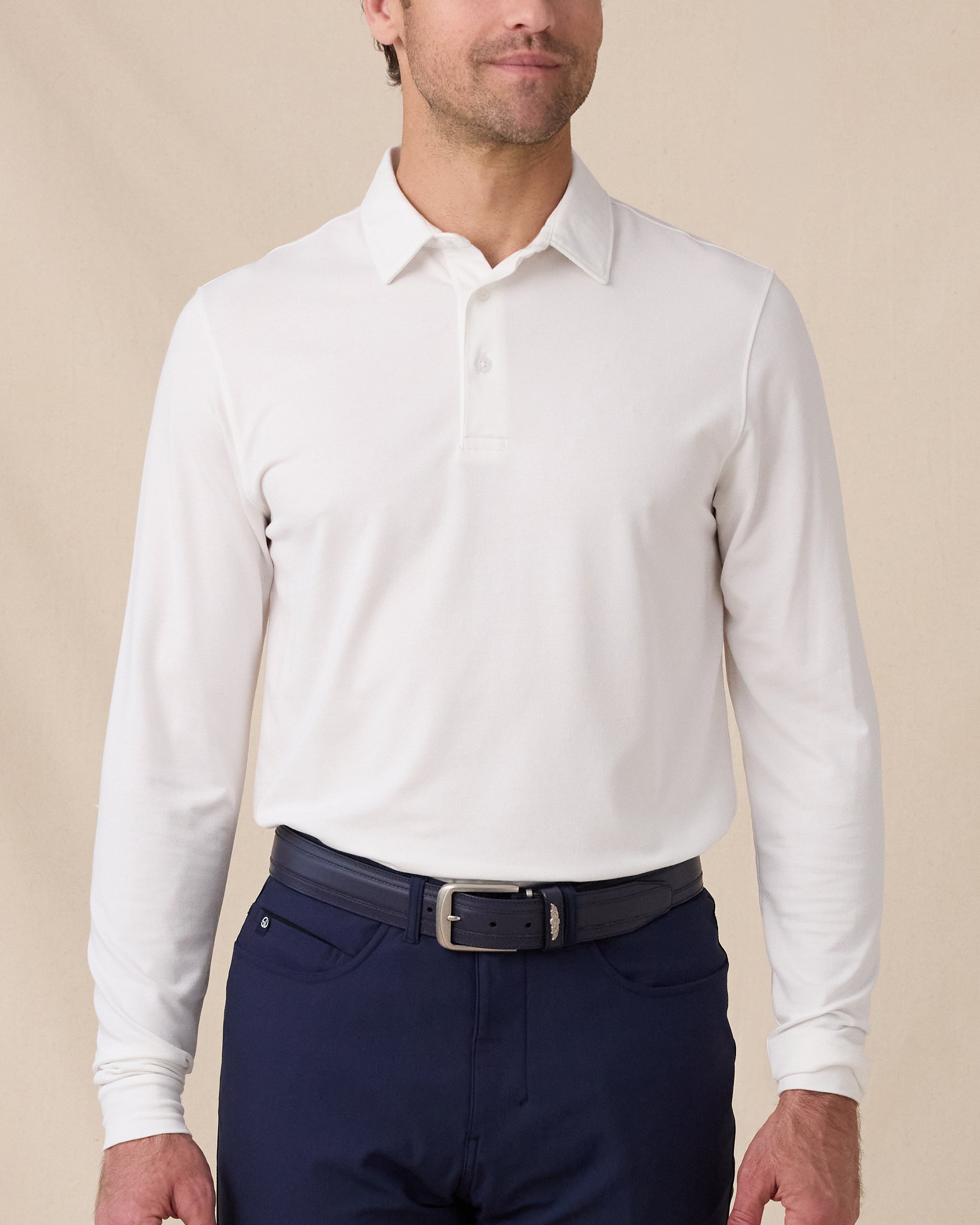 Model wearing the Cambridge Long Sleeve Polo in White, styled with navy golf pants