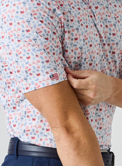 Grillin' Polo in White, on model close-up sleeve view highlighting the all-over scattered print in red and blue tones with Straight Down American flag logo tab on the sleeve