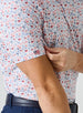 Grillin' Polo in White, on model close-up sleeve view highlighting the all-over scattered print in red and blue tones with Straight Down American flag logo tab on the sleeve