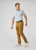 Men's Zuma Stripe Polo with White Base and Delphinium Blue & Soft Yellow Multi-Stripe Detailing, full body view on model paired with corduroy pants 