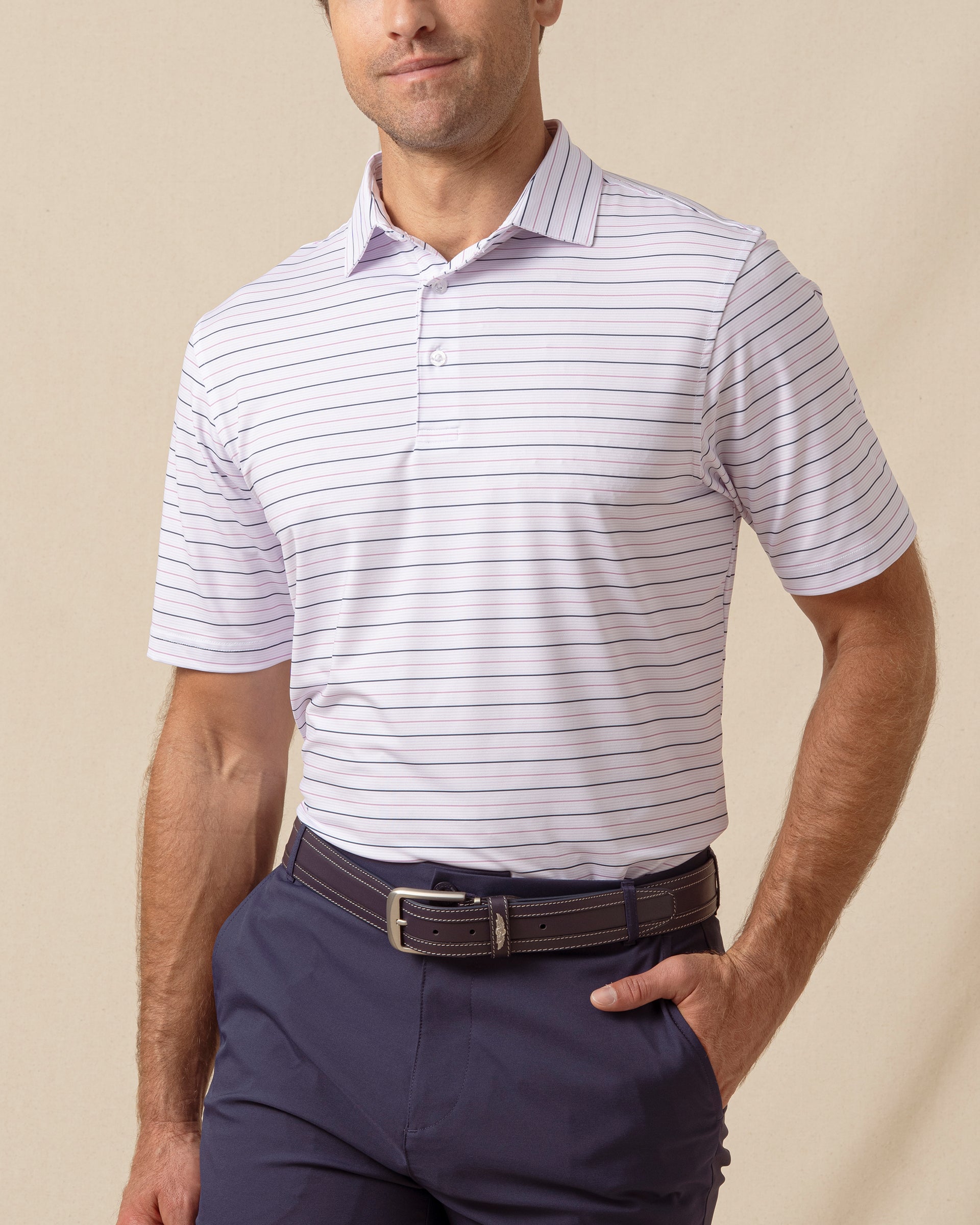 Men’s lilac polo with thin horizontal stripe pattern, short sleeves, and button placket, paired with navy pants