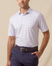 Men’s lilac polo with thin horizontal stripe pattern, short sleeves, and button placket, paired with navy pants