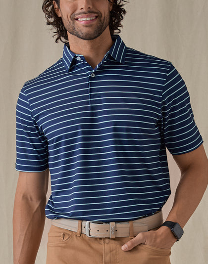 Men's Quintero Stripe Polo in Green Stone, front view on model featuring a navy base with light blue horizontal stripe pattern, paired with tan pants and a tan leather belt