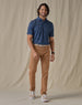 Men's Quintero Stripe Polo in Green Stone, full-length front view on model featuring a navy base with light blue horizontal stripe pattern, paired with tan pants, a tan leather belt, and tan and white shoes