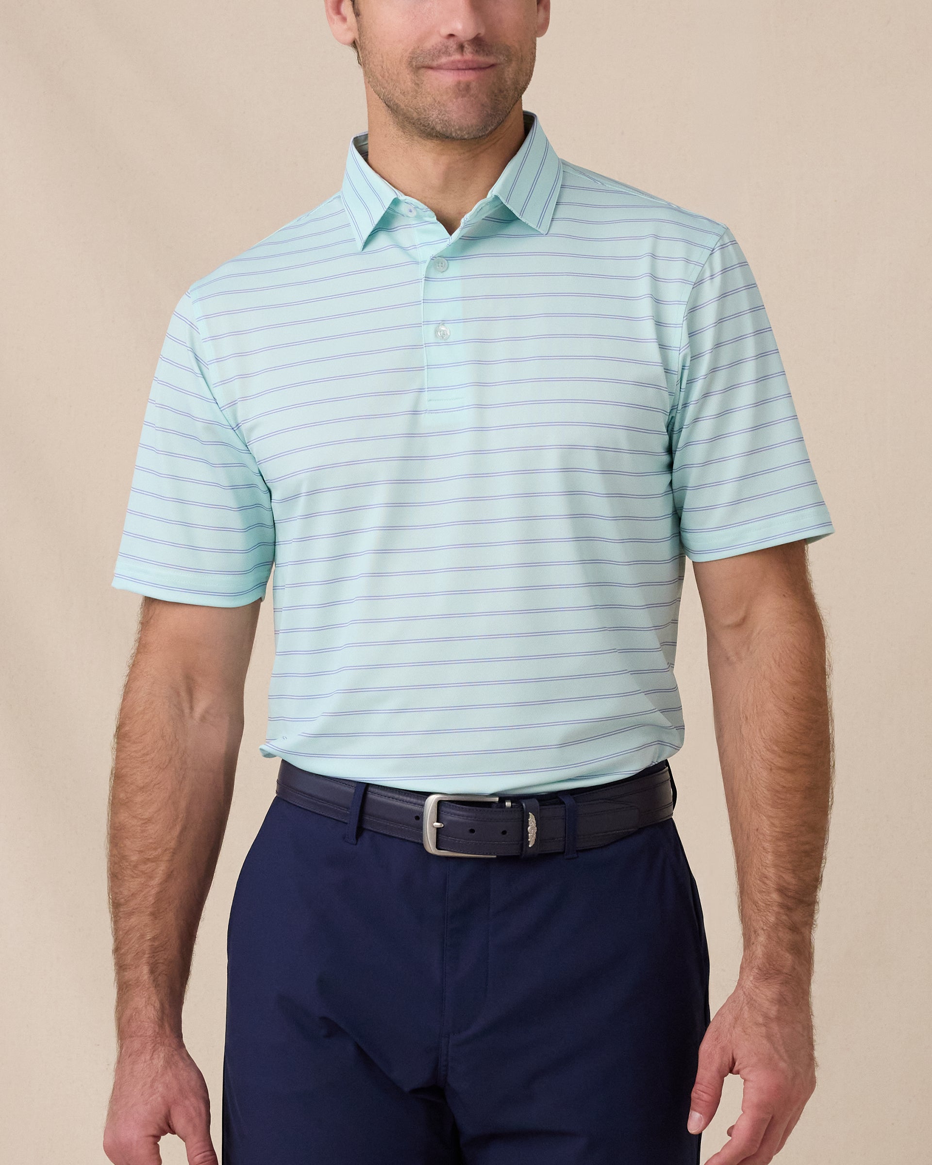 Man wearing the Quintero Stripe Polo in Mint Tea with navy pants and a matching belt.