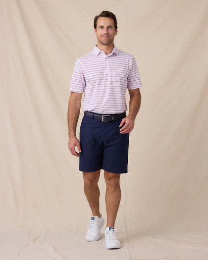 Model wearing the Quintero Stripe Polo in Lilac paired with navy golf shorts, a navy belt, and white golf shoes