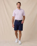 Model wearing the Quintero Stripe Polo in Lilac paired with navy golf shorts, a navy belt, and white golf shoes