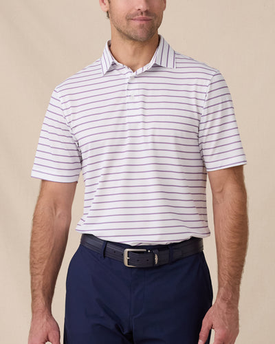 Model wearing the Quintero Stripe Polo in Tidal, a striped performance golf polo with blue and pink horizontal stripes