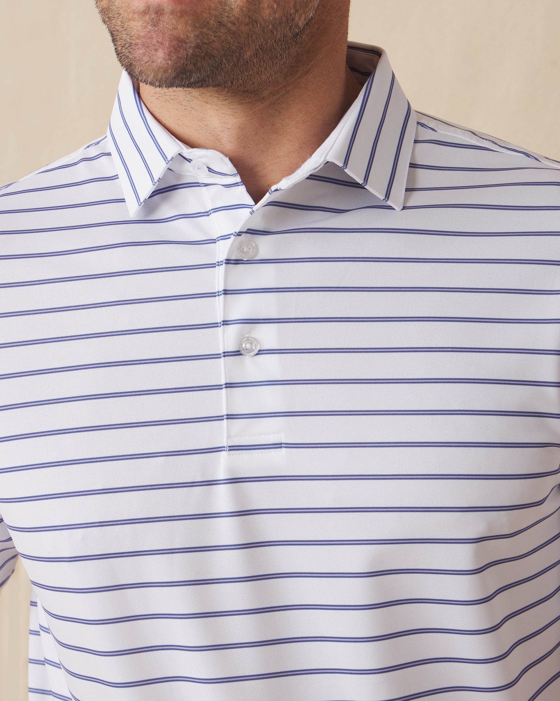 Men's Quintero Stripe Polo in Violet, close-up model view featuring the collar and button placket detail of a white short sleeve polo with horizontal blue and navy pencil stripes
