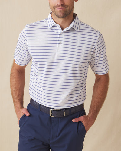 Men's Quintero Stripe Polo in Violet, front model view featuring a white short sleeve polo with horizontal blue and navy pencil stripes paired with navy pants and a navy belt