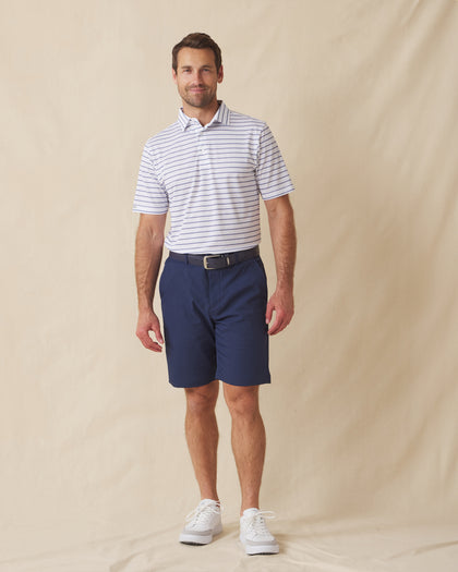 Men's Quintero Stripe Polo in Violet, full length model view featuring a white short sleeve polo with horizontal blue and navy pencil stripes paired with navy shorts and white shoes