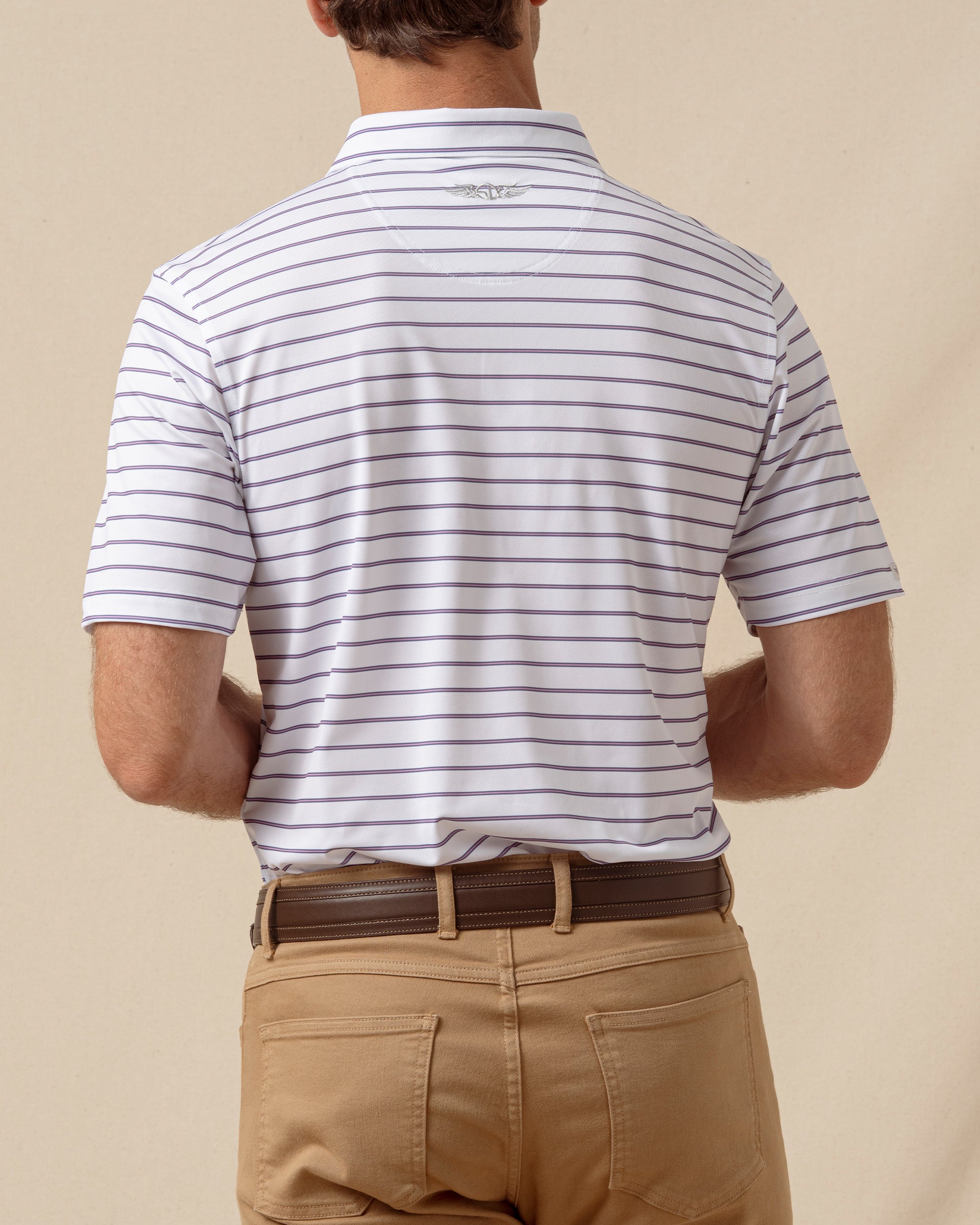 Back view of men’s striped polo with subtle logo detail, paired with tan pants