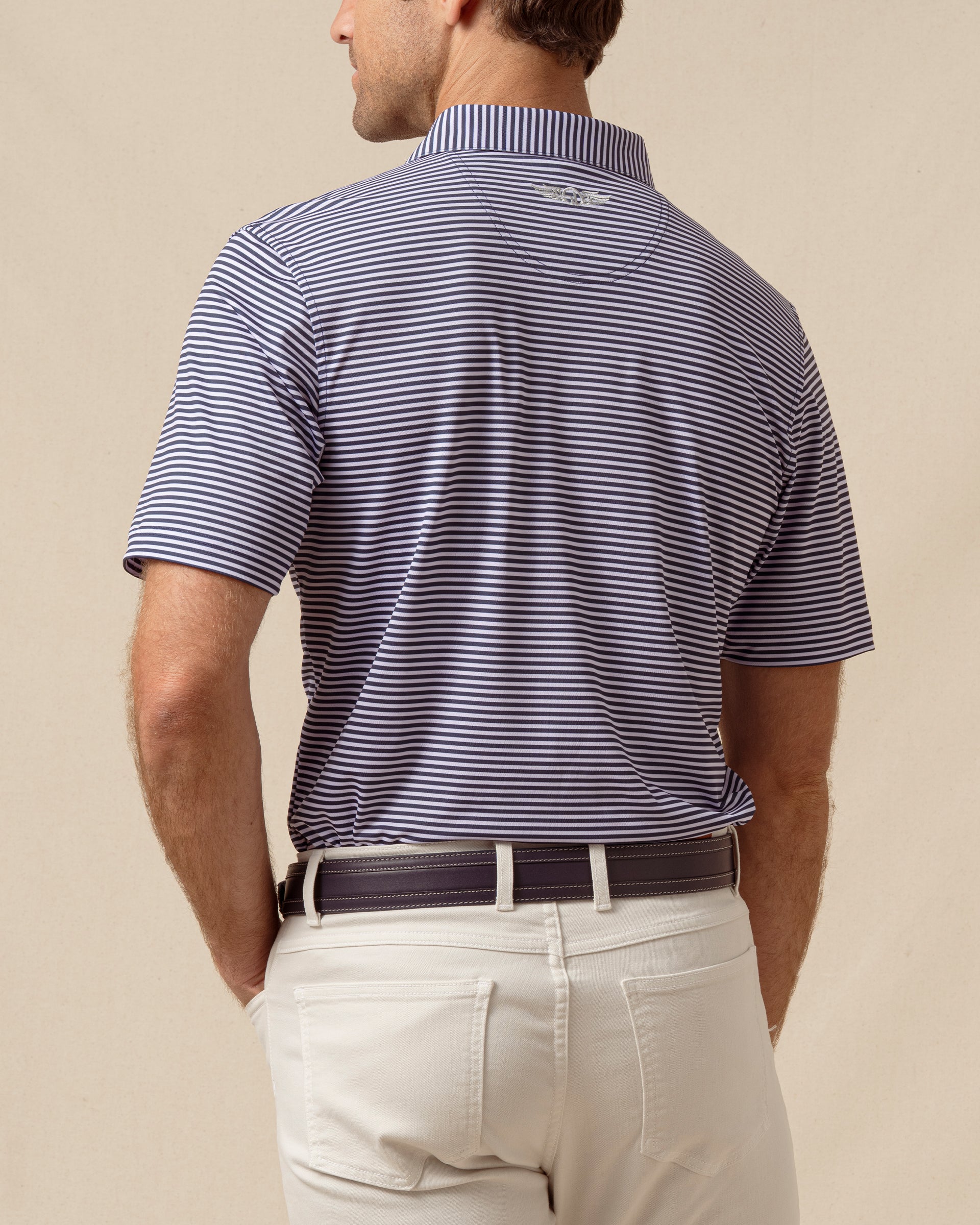 Men’s striped polo in indigo and lilac shown from the back with light khaki pants
