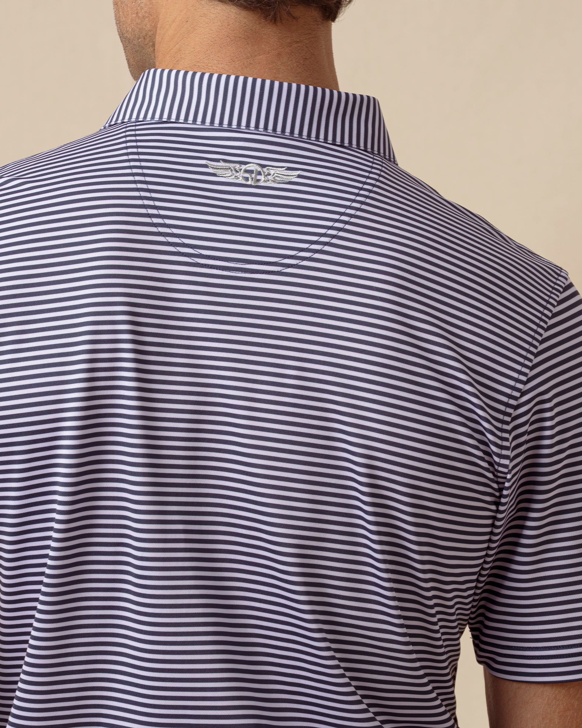 Back view of indigo and lilac striped polo featuring embroidered logo at the collar
