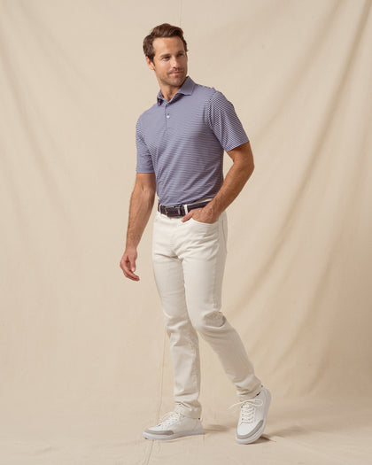 Men’s indigo and lilac striped polo styled with light khaki pants, belt, and white sneakers