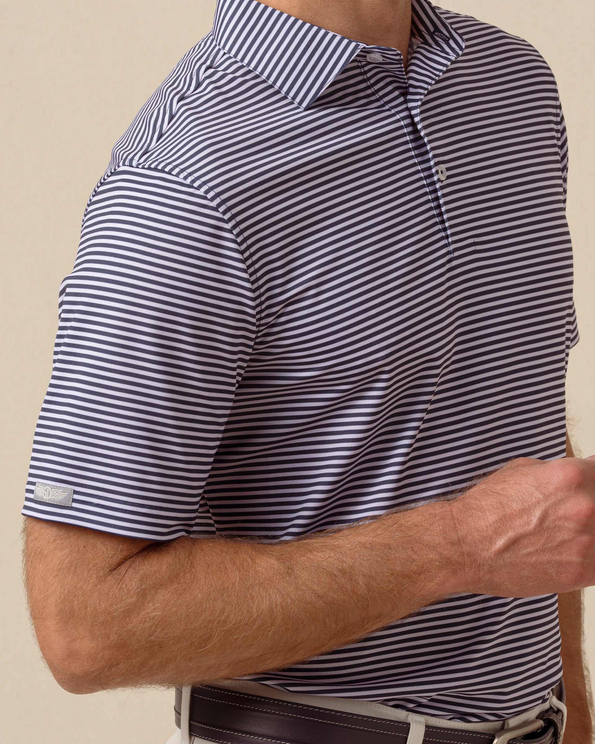 Close-up of indigo and lilac striped polo sleeve with embroidered logo detail