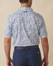 Men's Dorado Polo in Coastal, back view on model featuring a white base with a navy and blue tiled fish, floral, and bamboo stamp print, with Straight Down logo embroidered at upper back