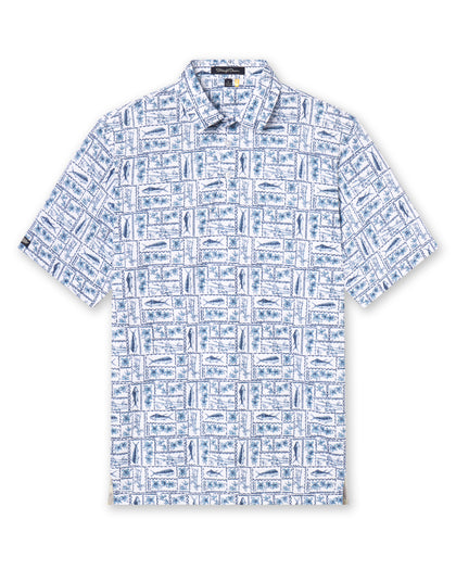 Men's Dorado Polo in Coastal, flat lay front view featuring a white base with a navy and blue tiled fish, floral, and bamboo stamp print, with Straight Down logo patch visible on sleeve