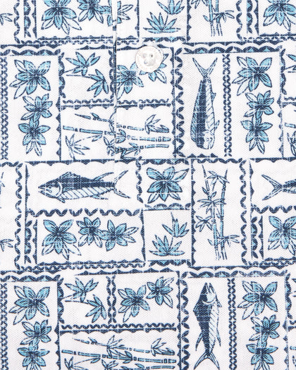 Men's Dorado Polo in Coastal, close-up flat lay fabric detail view highlighting the navy and blue tiled fish, floral, and bamboo stamp print on a white base