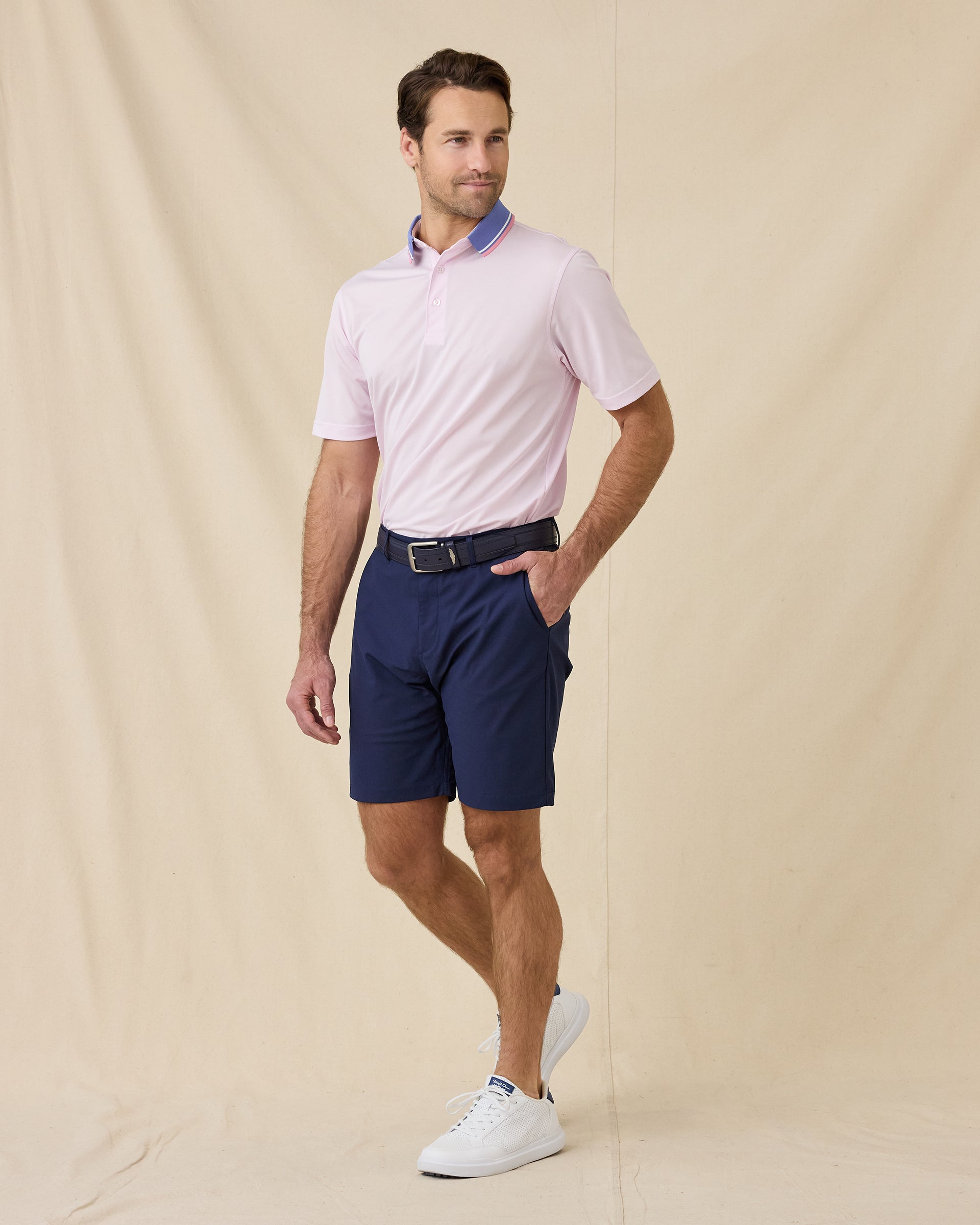 Model wearing the Chorro Polo in Lilac paired with navy golf shorts, a navy belt, and white golf shoes