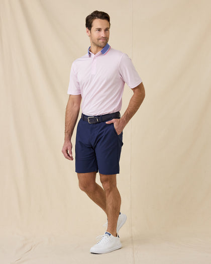 Model wearing the Chorro Polo in Lilac paired with navy golf shorts, a navy belt, and white golf shoes