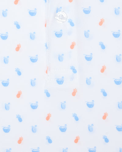 Men's Tropical Daze Polo in Carolina, close-up flat lay detail view featuring scattered pineapples and coconut drinks in sky blue and peach on a white ground with a branded button at the placket