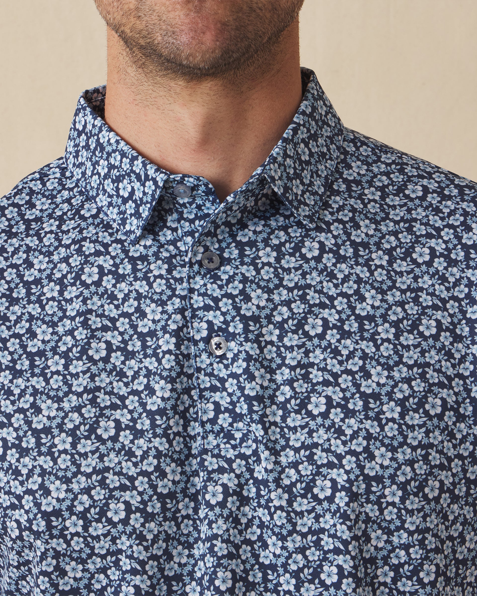 Men's Don Ho Polo in New Indigo, close-up front view on model highlighting the all-over light blue floral print on a navy base